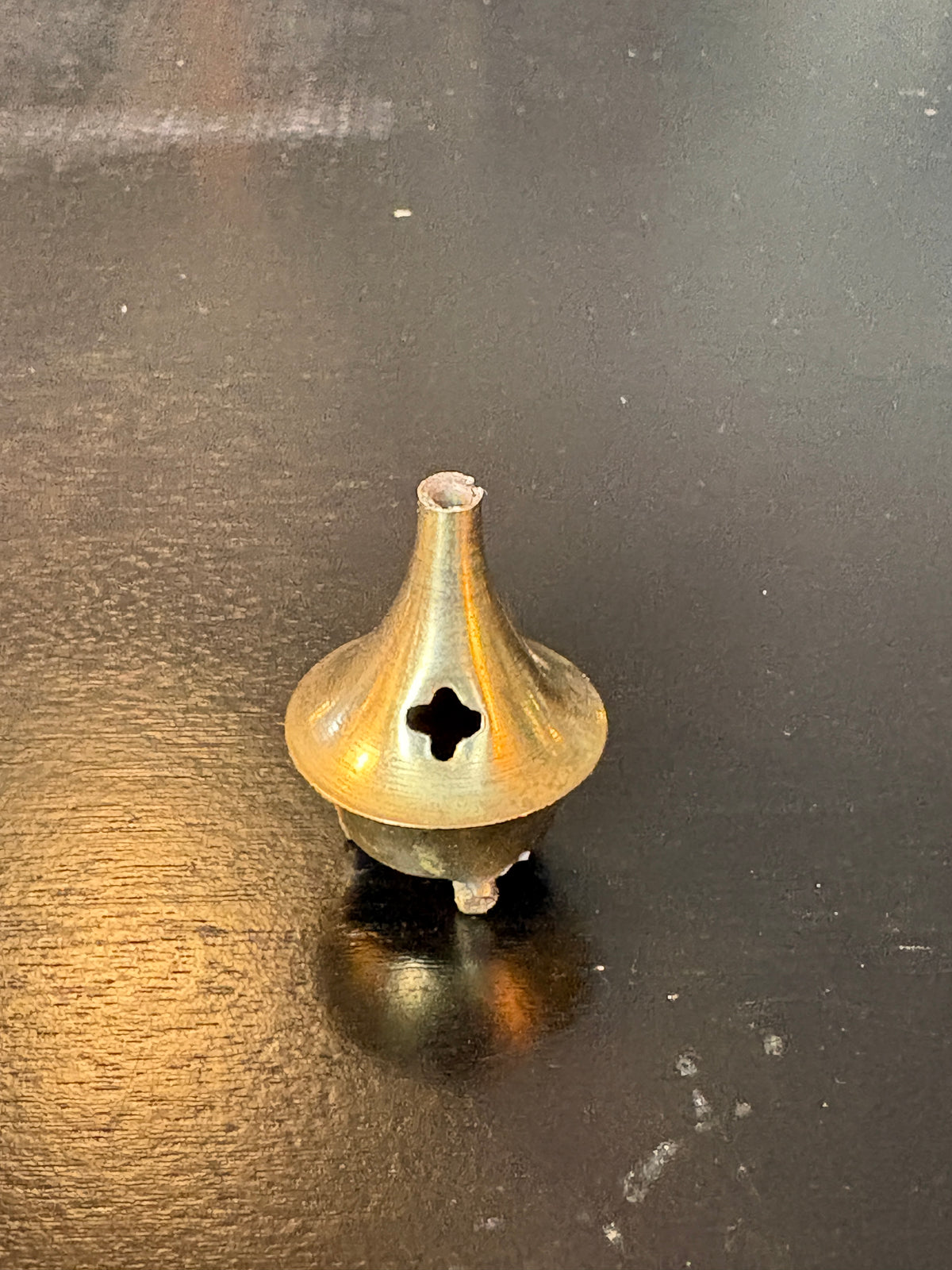 Small brass-tone incense cone with a quatrefoil opening, rounded base and raised feet